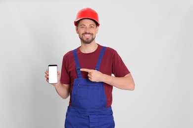 Professional repairman in uniform with phone on white background