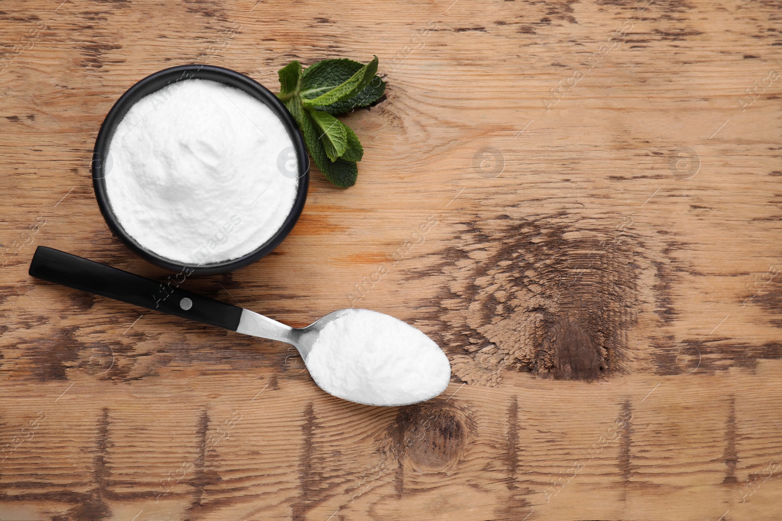 Photo of Sweet fructose powder and mint leaves on wooden table, flat lay. Space for text