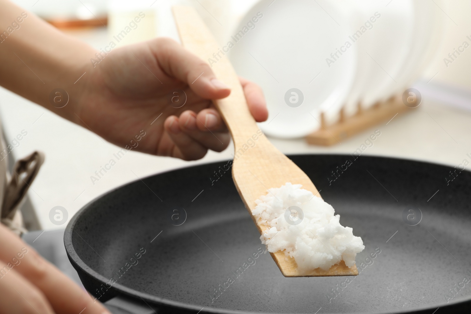 Photo of Woman cooking with coconut oil on induction stove, closeup