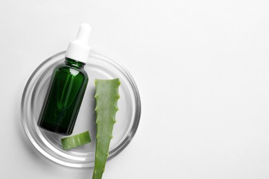 Petri dish with bottle of cosmetic product and aloe vera on white background, top view. Space for text