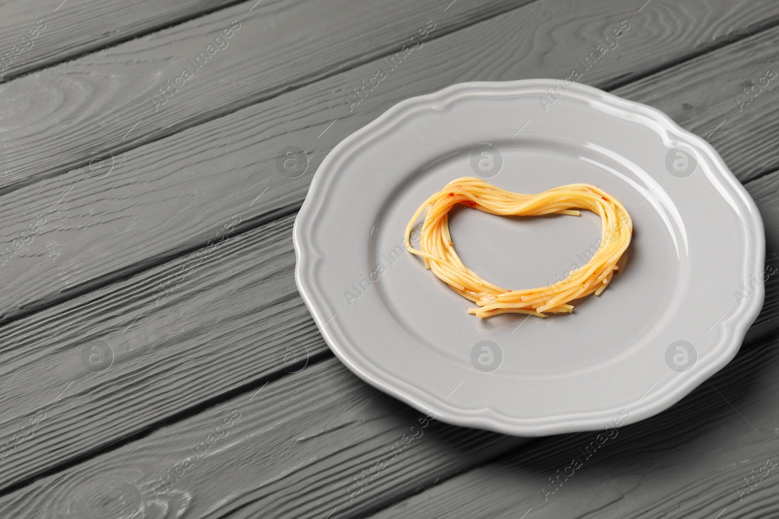 Photo of Heart made with spaghetti on grey wooden table