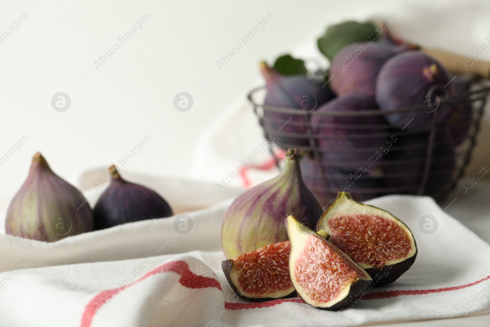 Photo of Tasty cut and whole figs on table with napkin