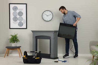 Photo of Man installing electric fireplace near wall in room