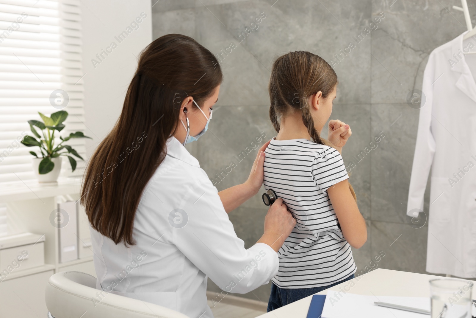 Photo of Doctor examining coughing girl in hospital. Cold symptoms