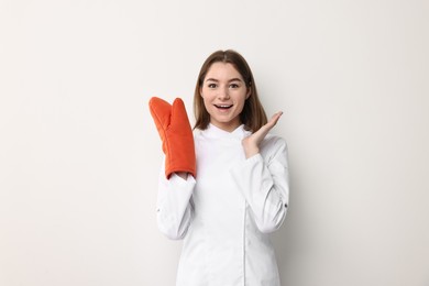 Photo of Professional chef with oven glove on light background