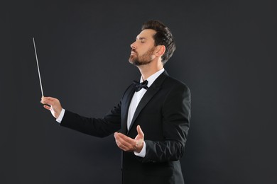 Professional conductor with baton on black background