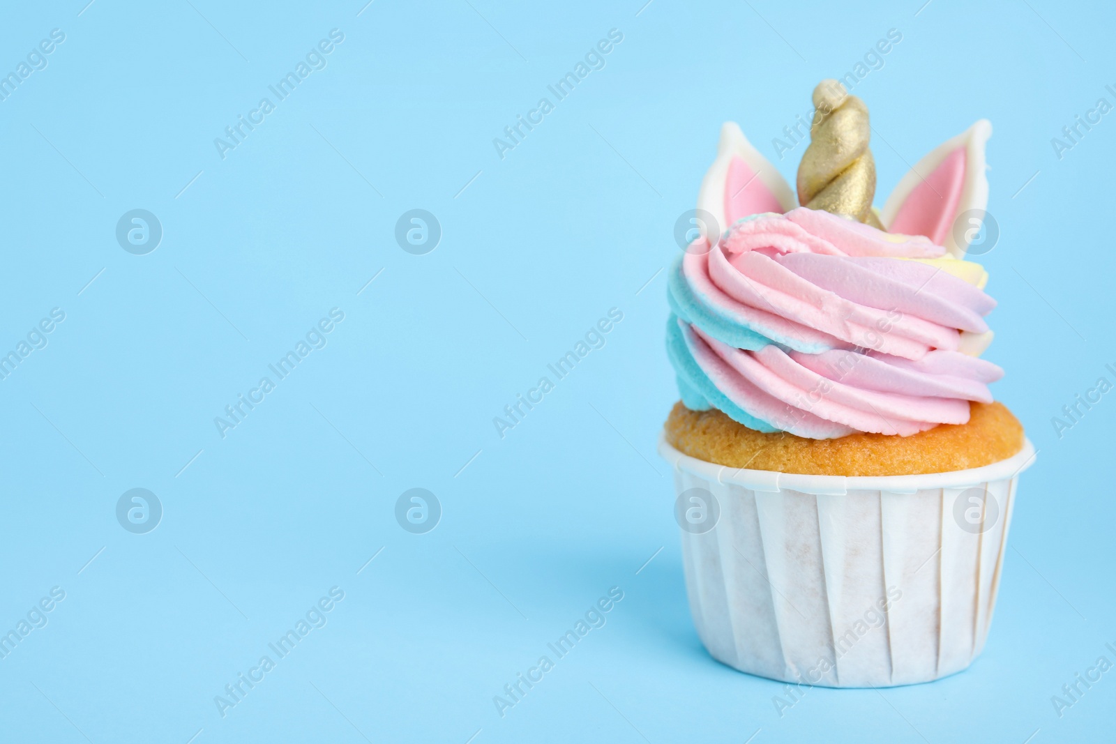 Photo of Cute sweet unicorn cupcake on light blue background. Space for text