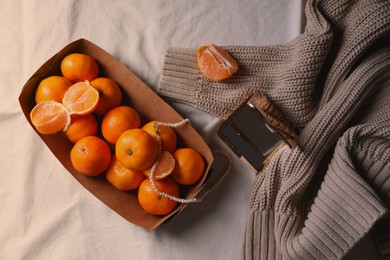 Paper box with fresh ripe tangerines and decor on white cloth, flat lay