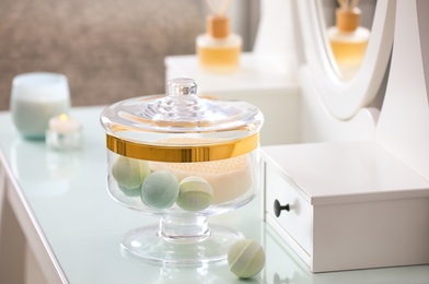 Photo of Jar with bath bombs and bath sponge on dressing table indoors