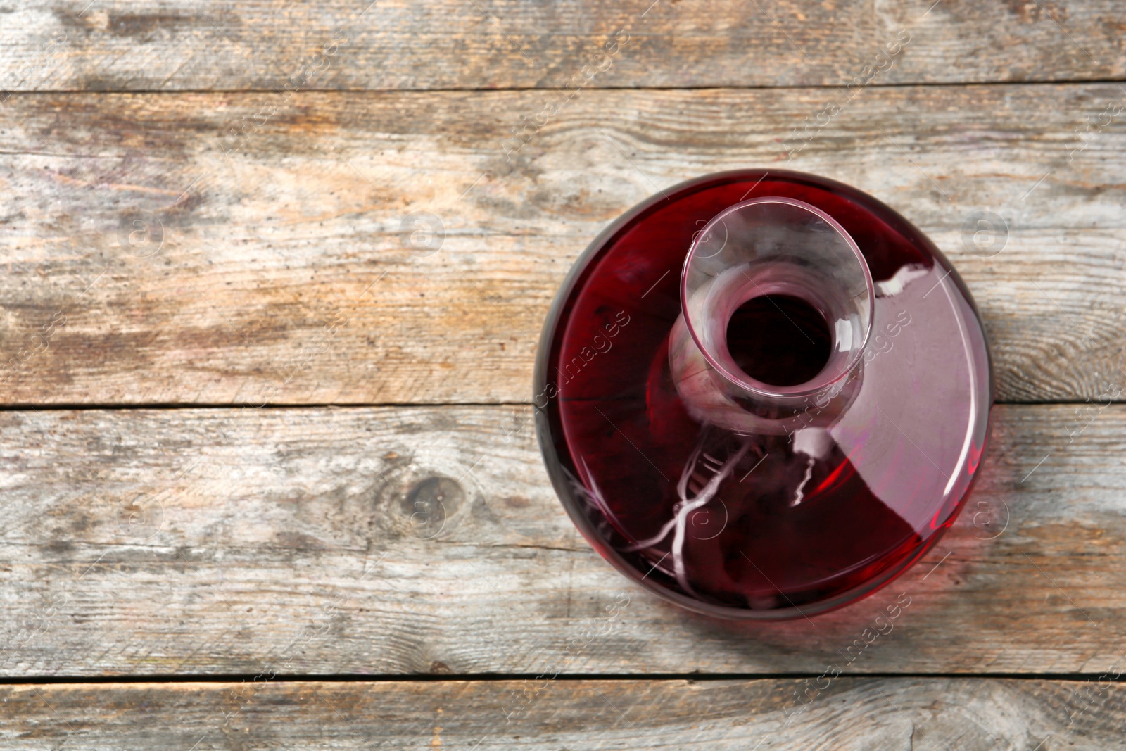 Photo of Decanter with red wine on wooden background, top view