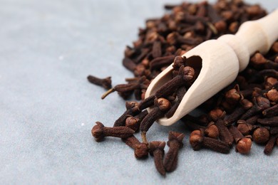 Photo of Pile of aromatic dried clove buds and scoop on grey table, closeup. Space for text