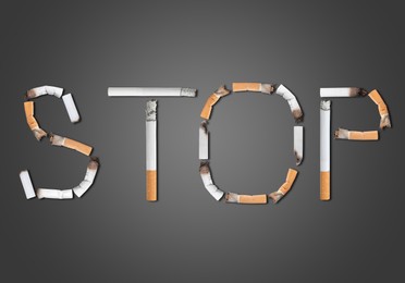 Image of Quitting smoking concept. Word Stop made of burnt cigarettes on grey background, flat lay