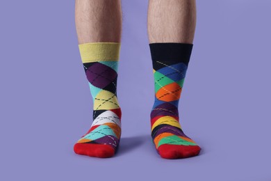 Photo of Man in different colorful socks on violet background, closeup