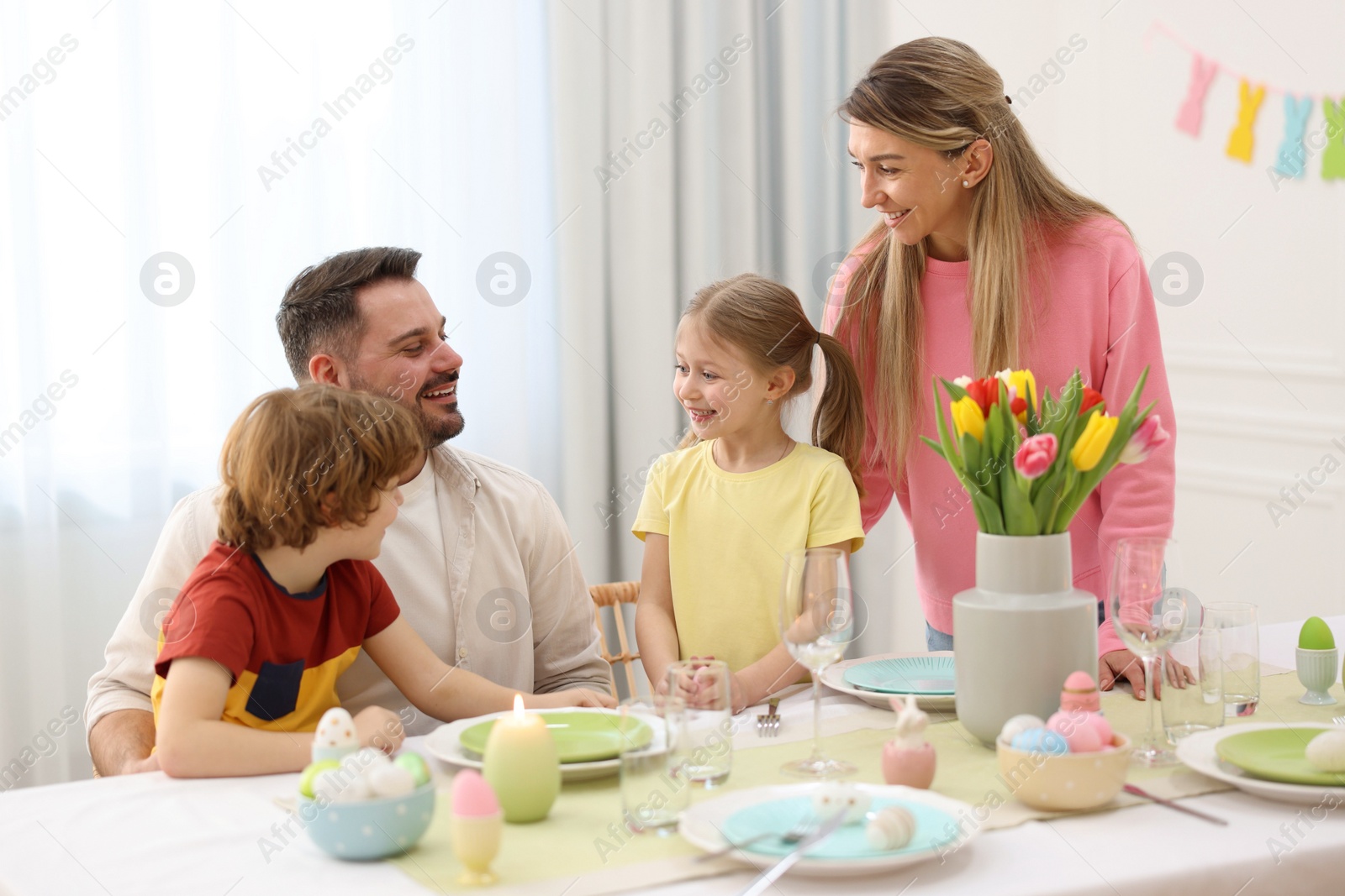 Photo of Happy family celebrating Easter at served table in room