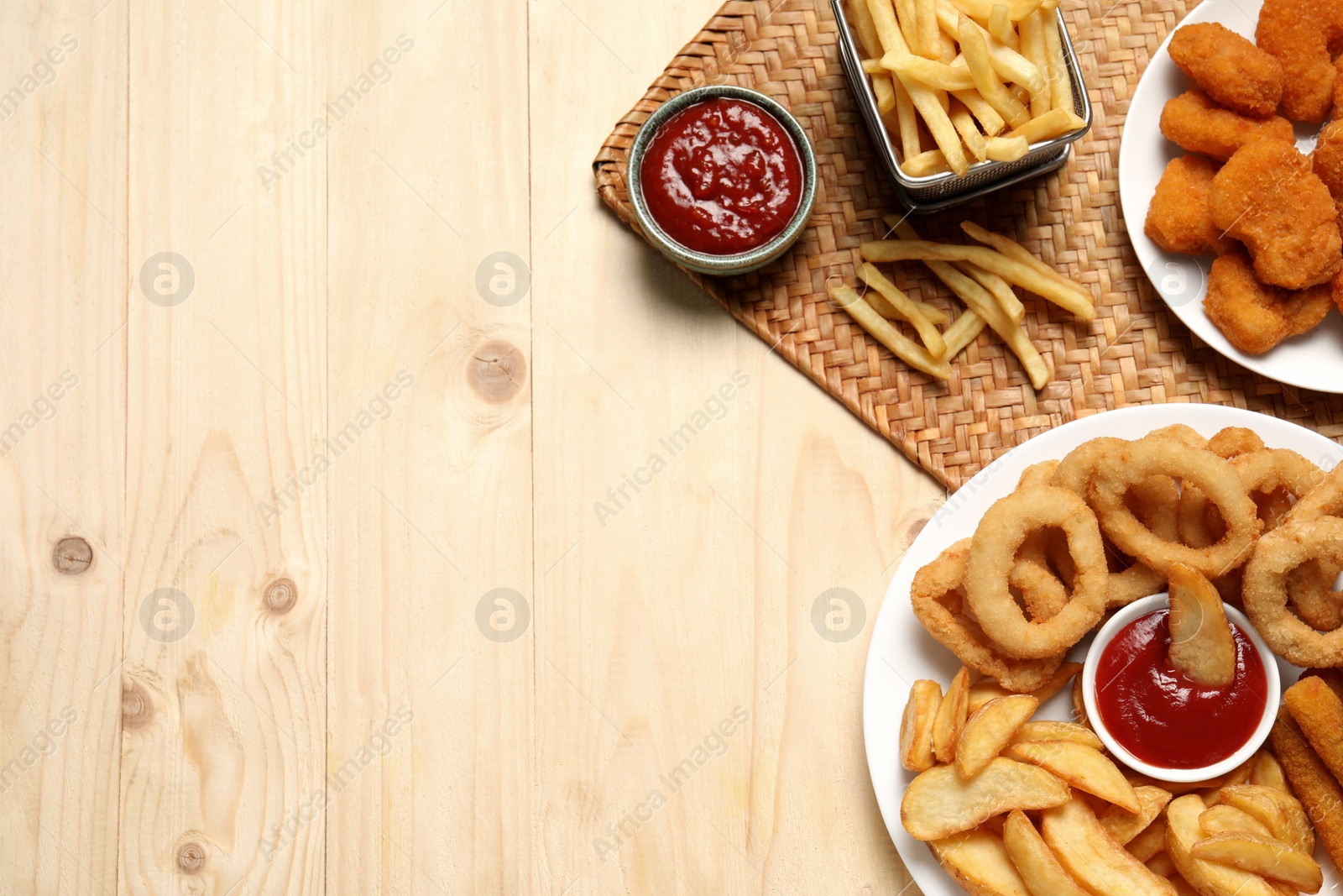 Photo of Different snacks and tasty ketchup on wooden table, flat lay. Space for text