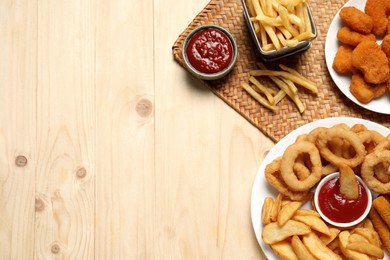 Different snacks and tasty ketchup on wooden table, flat lay. Space for text