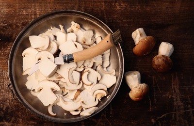 Photo of Knife, cut and whole mushrooms on wooden table, flat lay