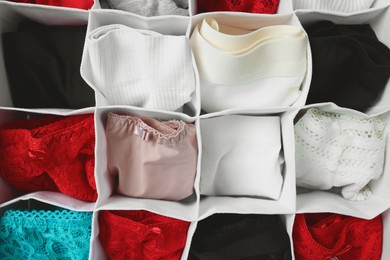 Photo of Organizer with folded women's underwear as background, top view