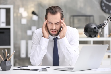 Young man suffering from headache in office