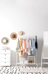 Photo of Rack with stylish women's clothes and mirror indoors. Interior design