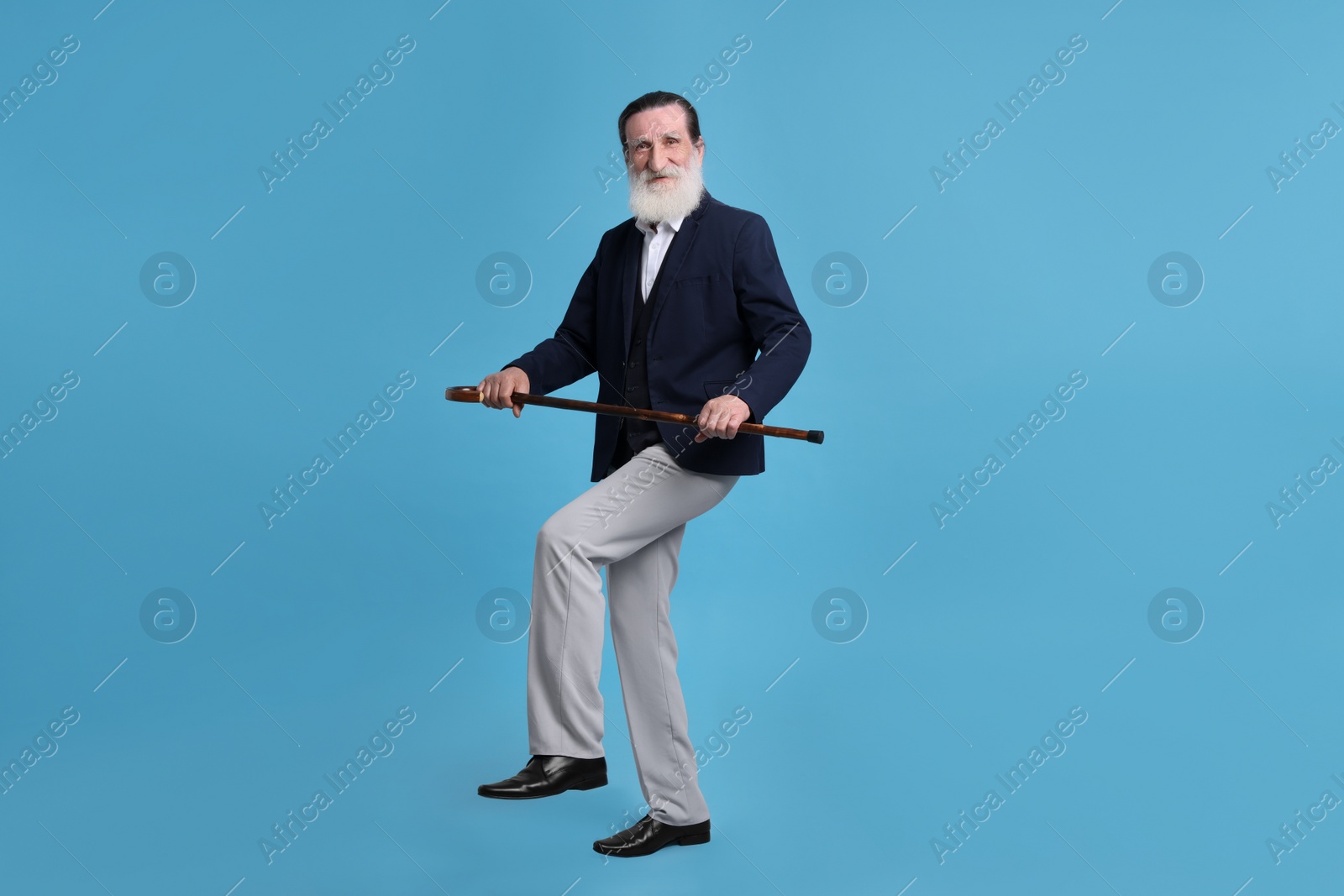 Photo of Senior man with walking cane on light blue background