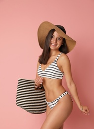 Photo of Pretty sexy woman with slim body in stylish  striped bikini on coral background