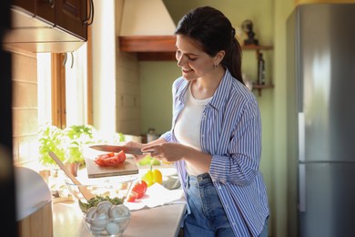 Photo of Young woman preparing salad at countertop in kitchen