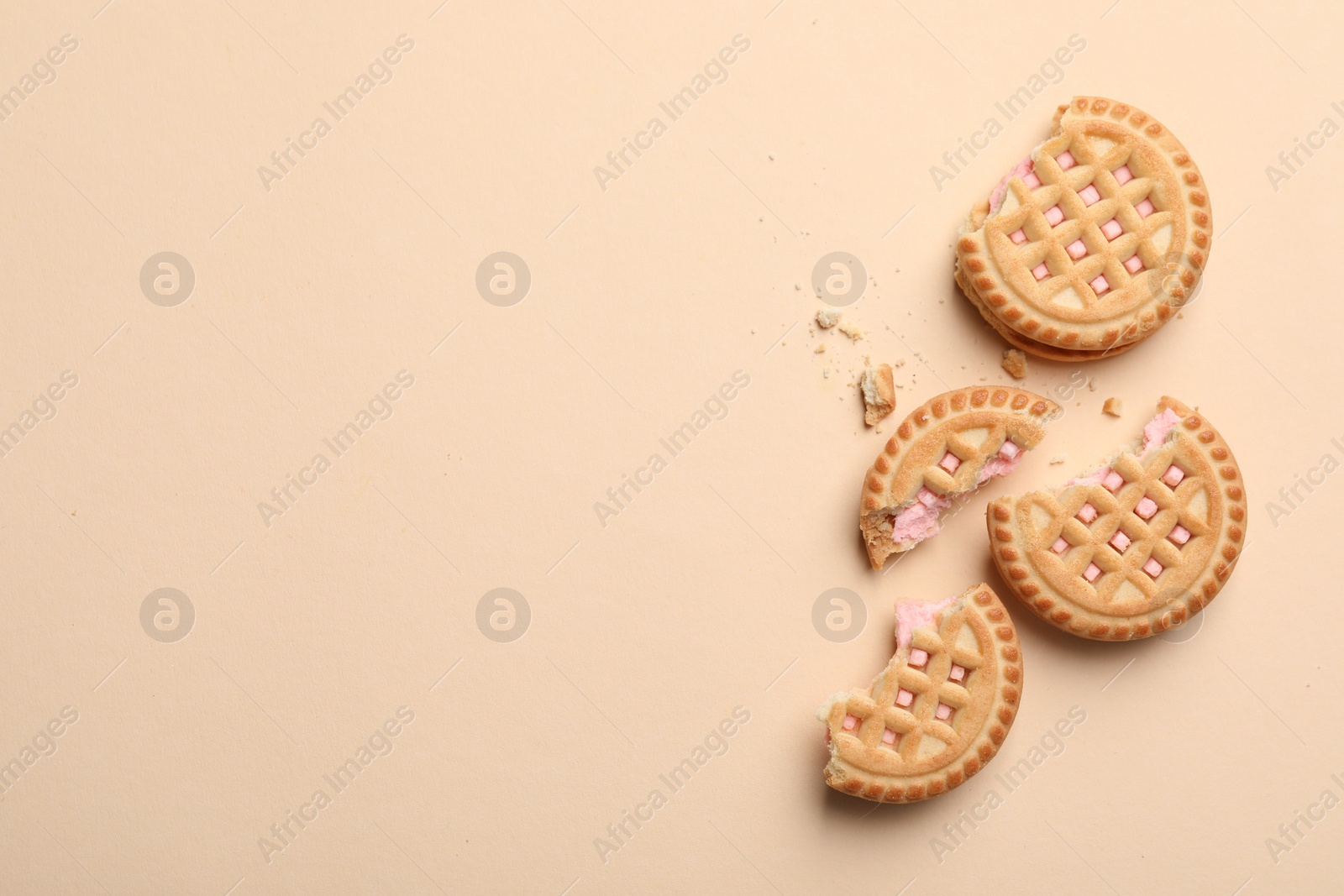 Photo of Tasty sandwich cookies with cream on beige background, flat lay. Space for text