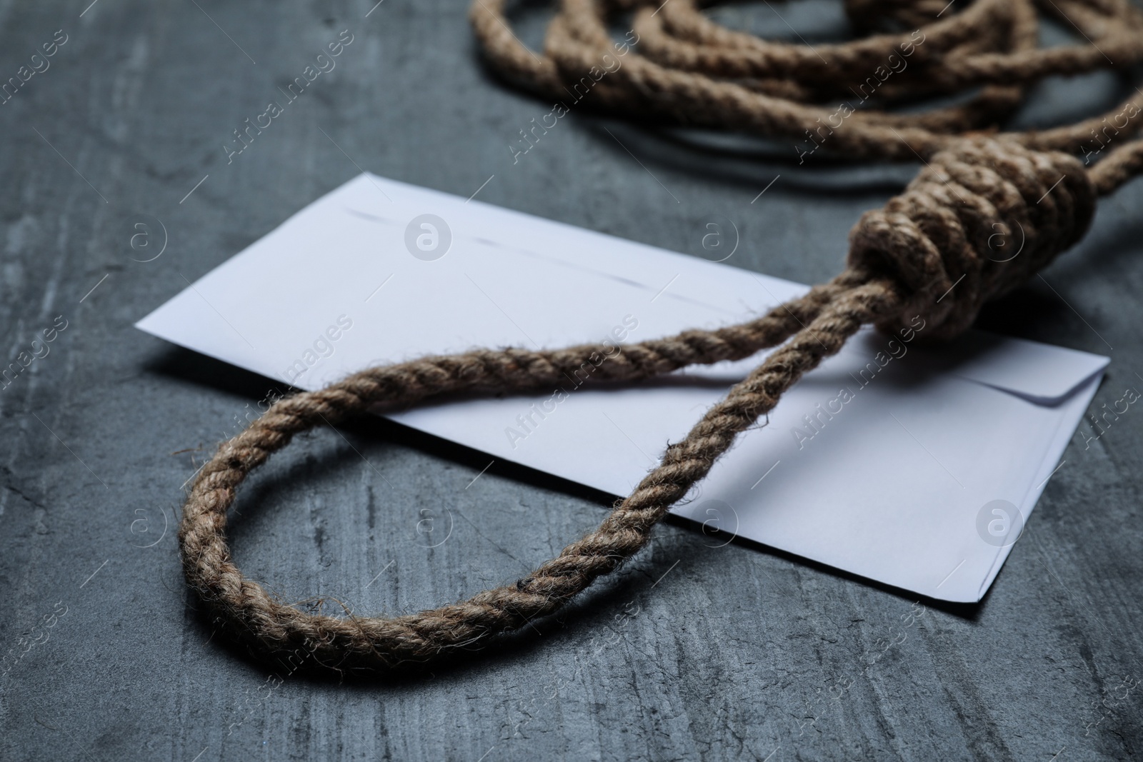 Photo of Rope noose and blank envelope on black table, closeup