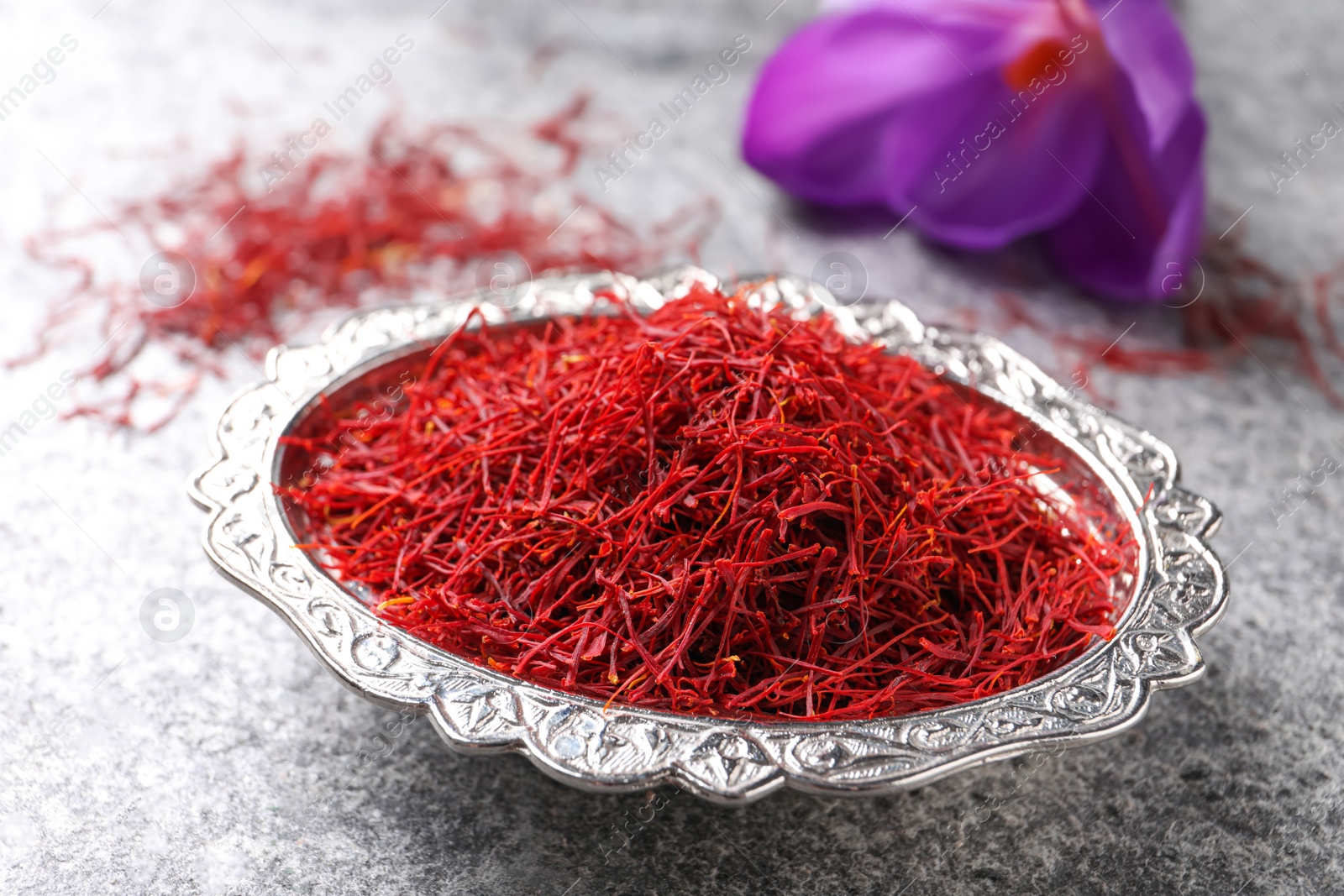 Photo of Dried saffron and crocus flower on grey table, closeup