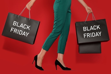 Woman with shopping bags on red background, closeup. Black Friday