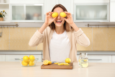 Photo of Young woman having fun while making lemon water in kitchen
