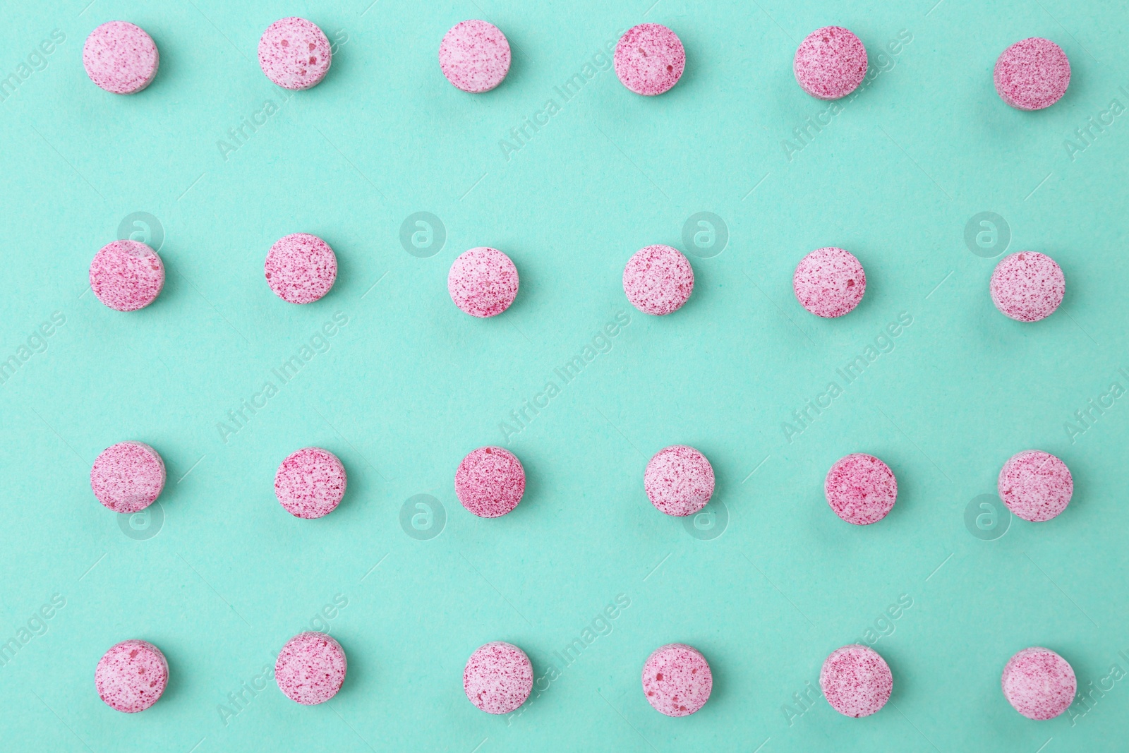 Photo of Many pink vitamin pills on turquoise background, flat lay