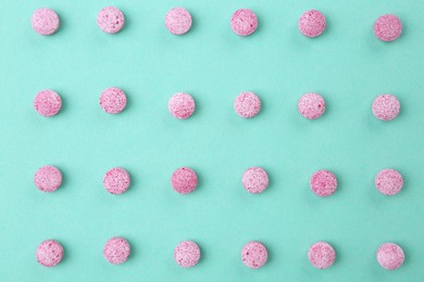 Photo of Many pink vitamin pills on turquoise background, flat lay