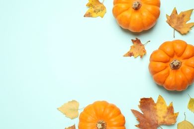 Fresh ripe pumpkins and autumn leaves on light blue background, flat lay. Space for text