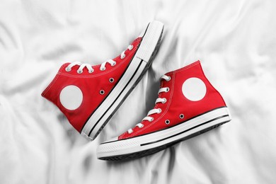 Pair of new stylish red sneakers on white fabric, flat lay