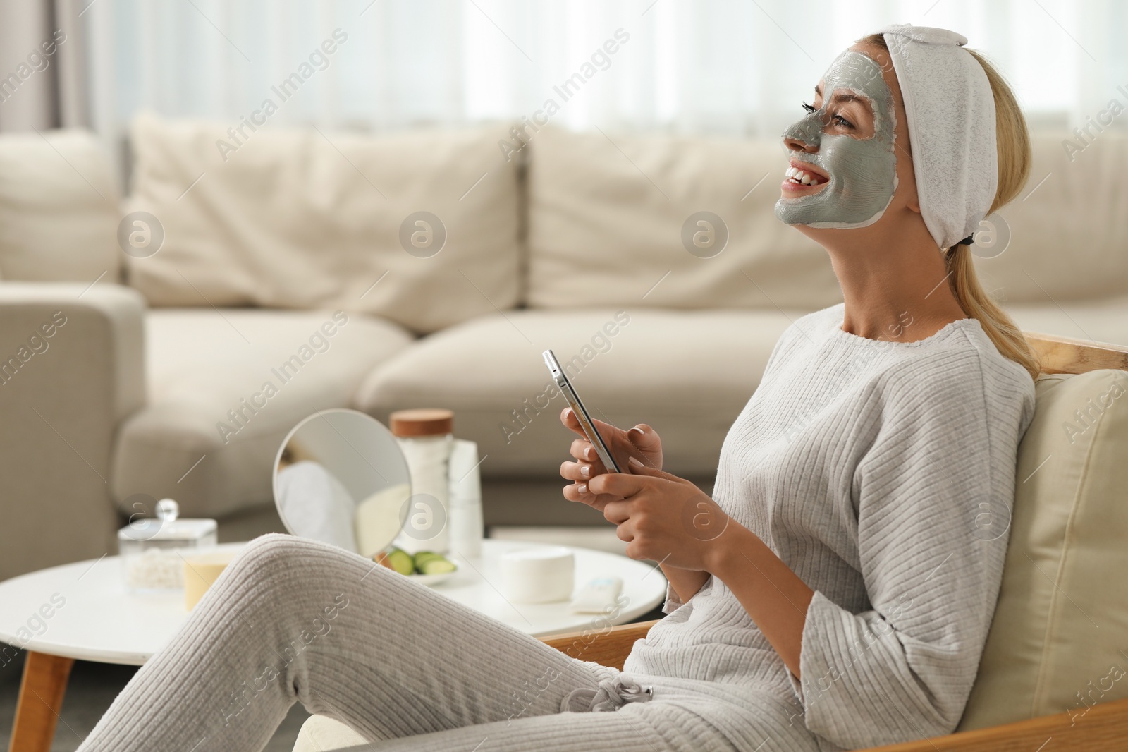 Photo of Young woman with face mask using smartphone at home, space for text. Spa treatments