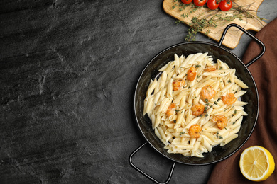 Delicious pasta with shrimps served on black table, flat lay. Space for text