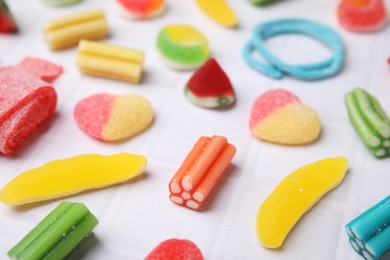 Photo of Many tasty colorful jelly candies on white tiled table, closeup