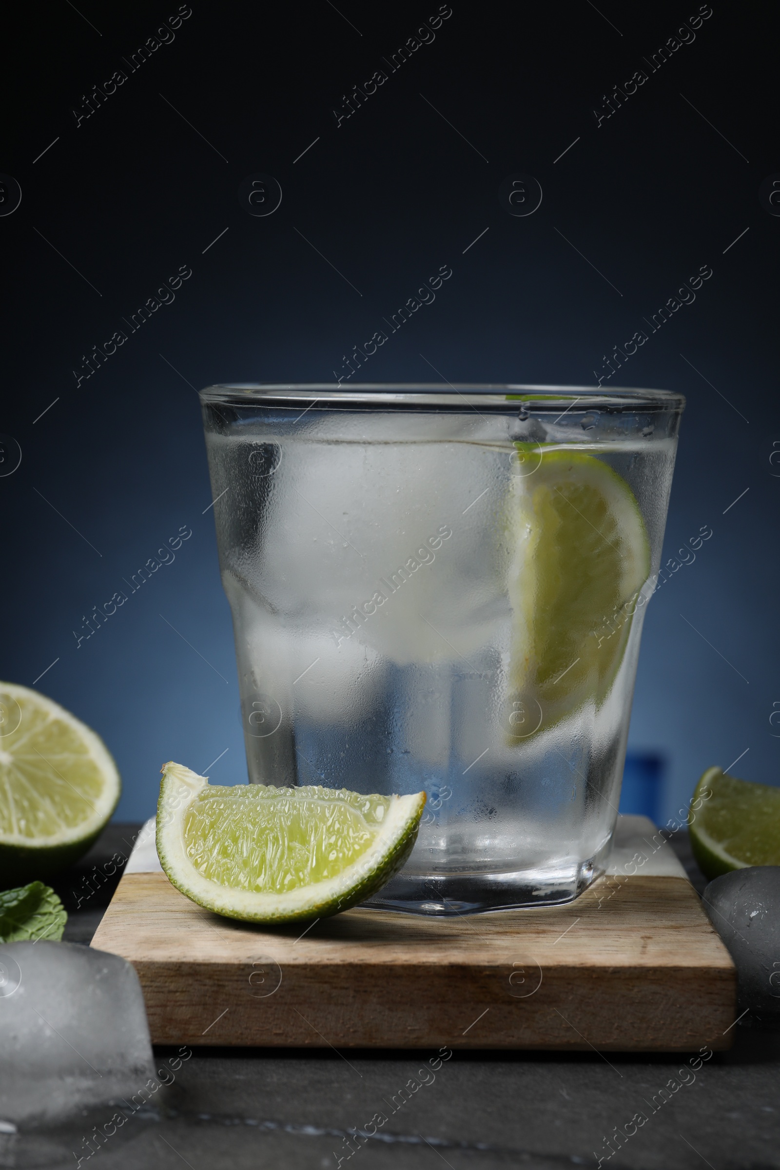 Photo of Glass of vodka with lime and ice on black marble table