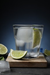 Glass of vodka with lime and ice on black marble table