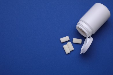 Jar with chewing gums on blue background, flat lay. Space for text