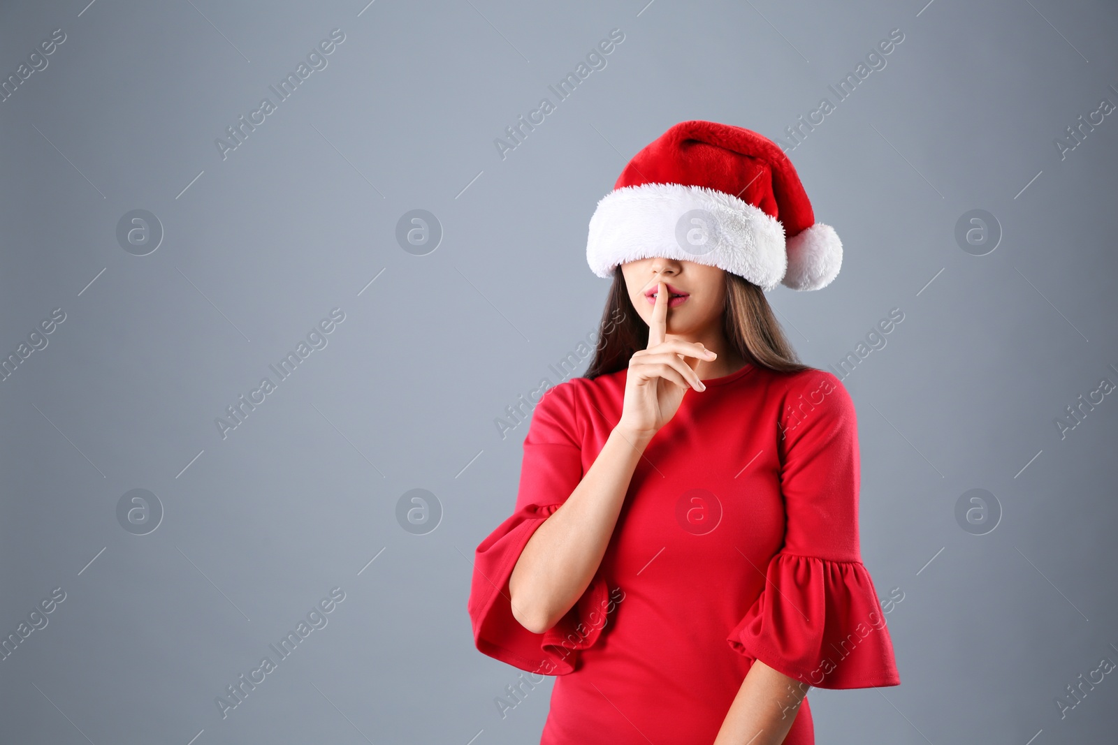 Photo of Young beautiful woman in Santa hat on grey background. Christmas celebration