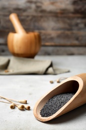 Photo of Wooden scoop with poppy seeds on table
