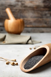 Wooden scoop with poppy seeds on table