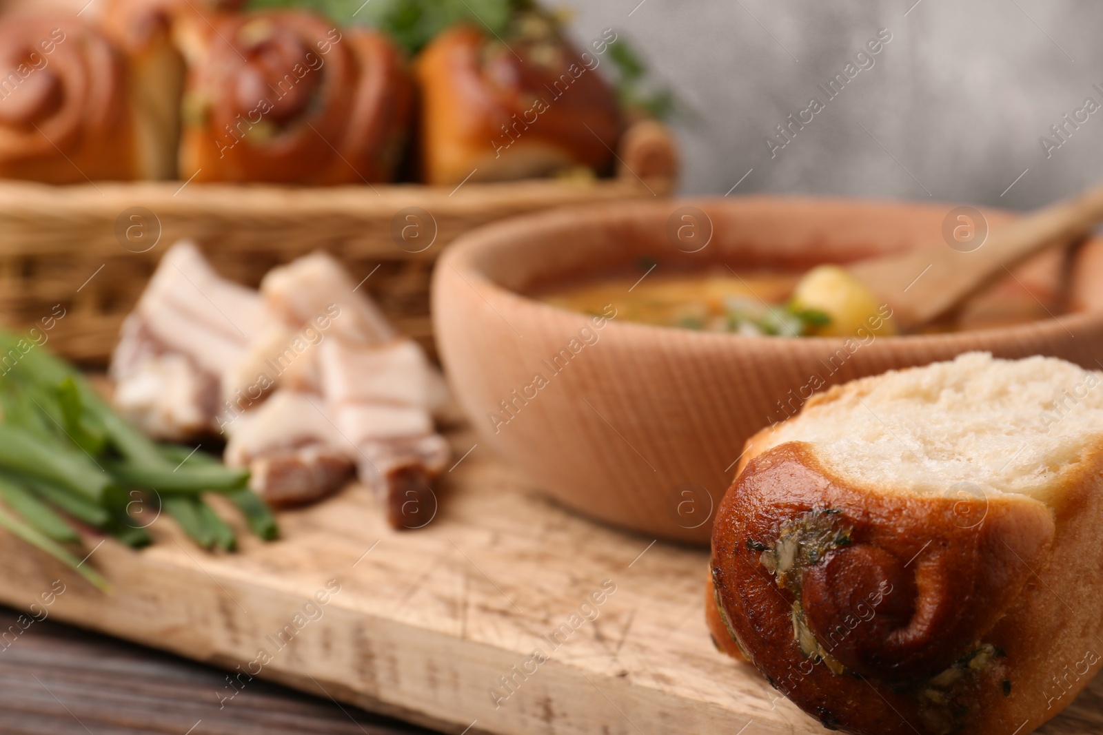 Photo of Delicious borsch served with pampushky and salo on wooden table, closeup. Traditional Ukrainian cuisine