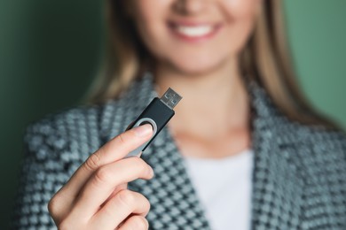 Photo of Woman holding usb flash drive against green background, focus on hand