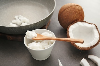 Photo of Bowl with coconut oil and nut pieces on grey background