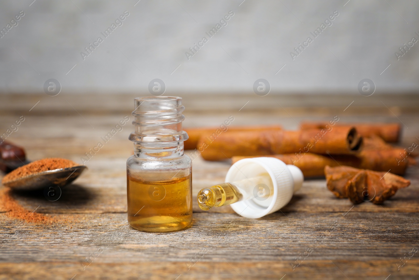 Photo of Bottle and pipette with cinnamon essential oil on wooden table