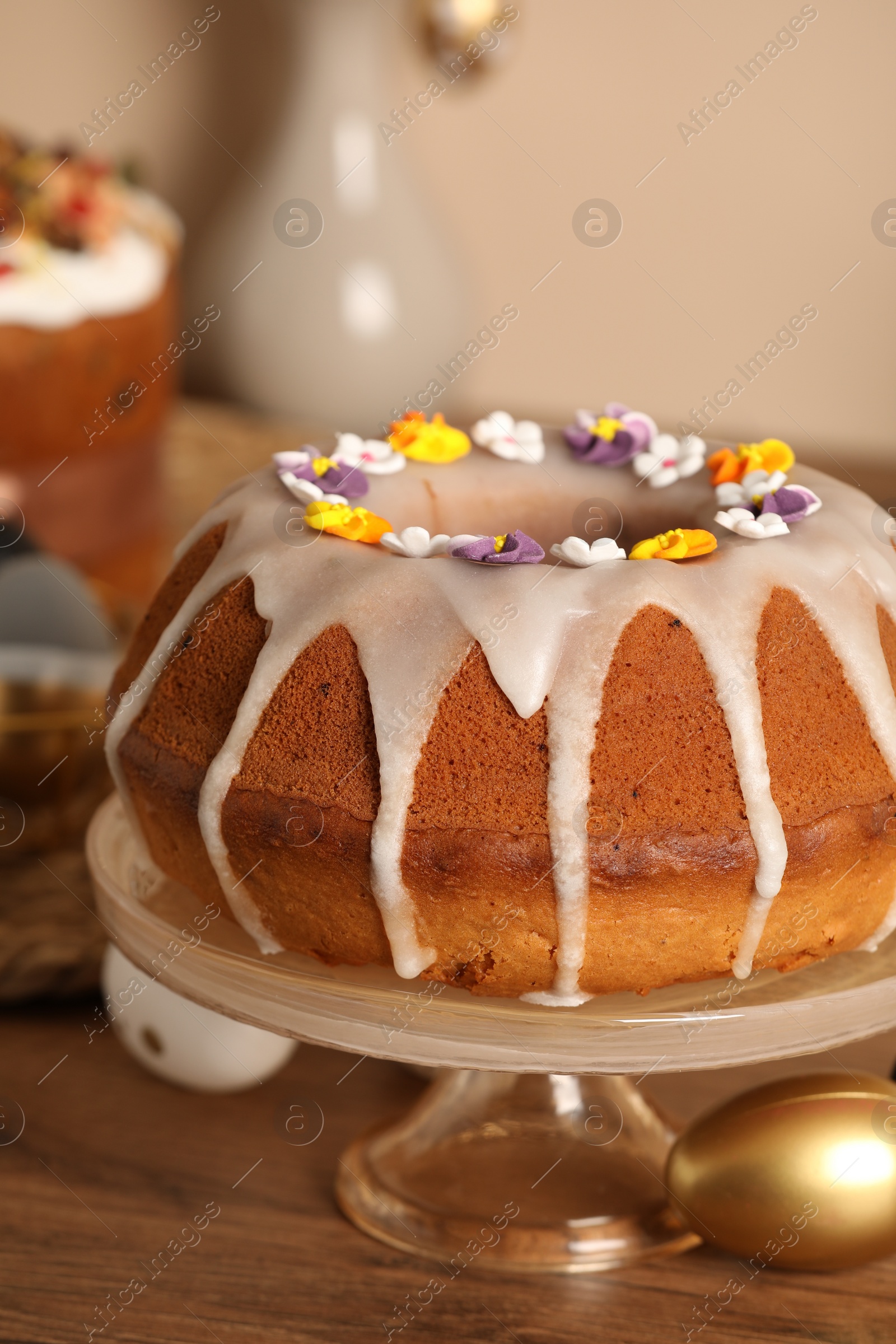 Photo of Delicious Easter cake decorated with sprinkles near painted eggs on wooden table, closeup